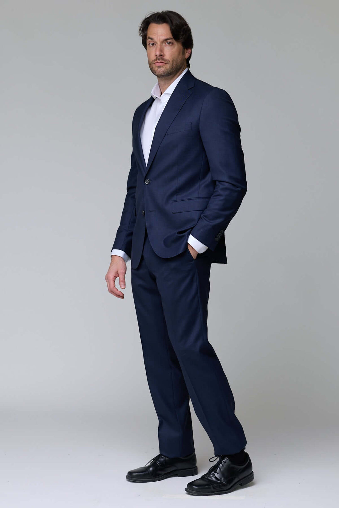 Homme portant un complet classique deux pièces élégant, bleu marine, idéal pour bureau et événements formels.