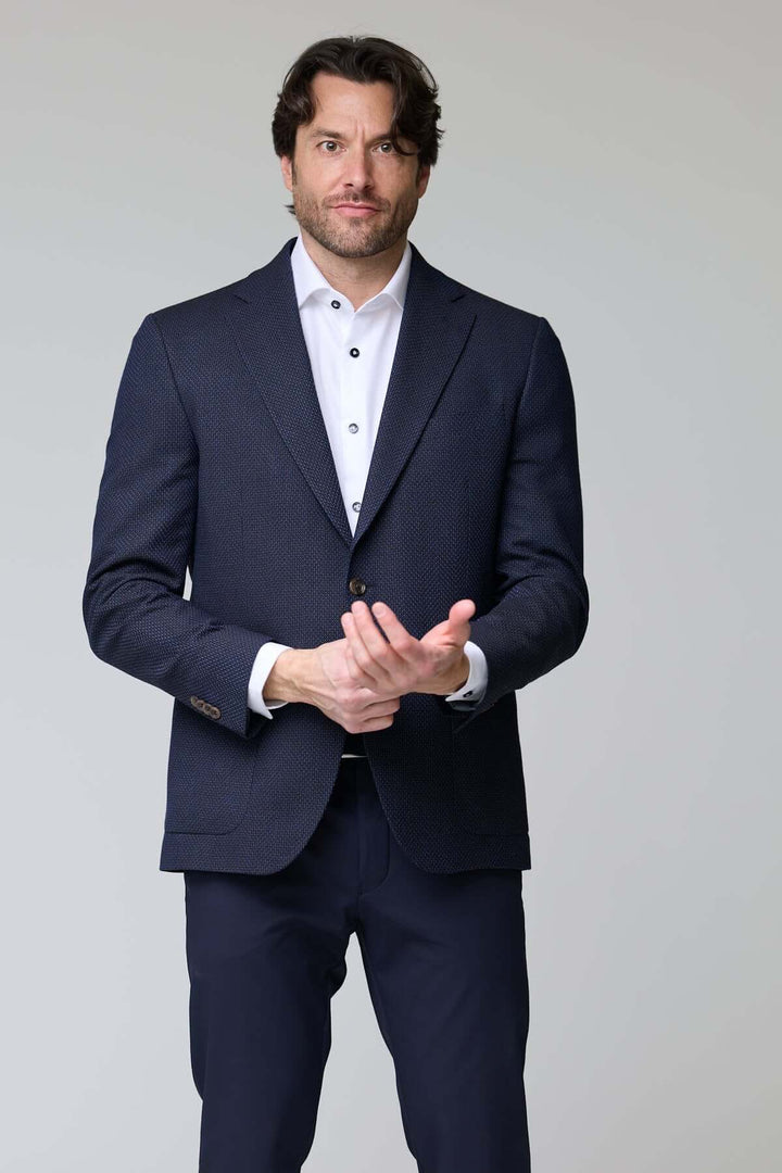 Homme portant un veston texturé à coupe moderne, élégant et confortable, idéal pour le bureau ou les sorties habillées.