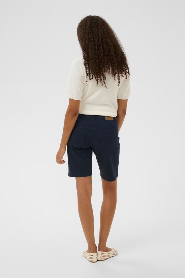 Bermuda classique coupe droite, femme de dos portant un bermuda bleu, taille mi-haute avec poches et passants de ceinture.