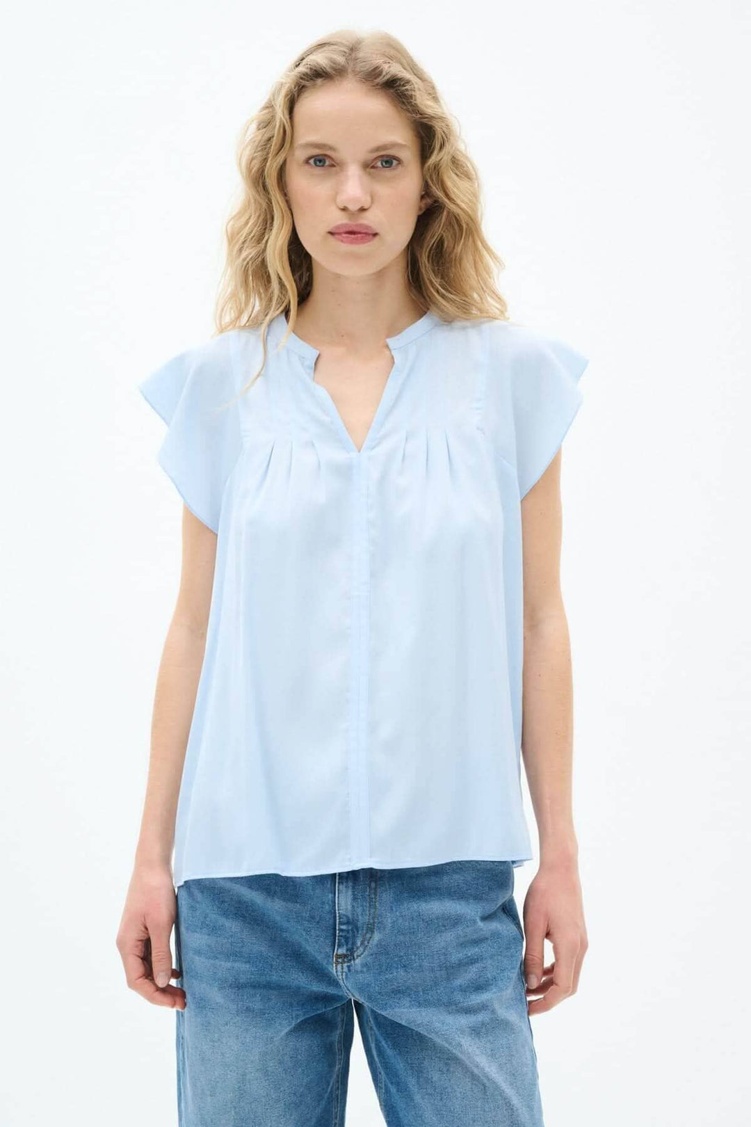 Blouse légère Cidenza en bleu clair avec encolure plissée et manches volantes, style féminin et élégant.