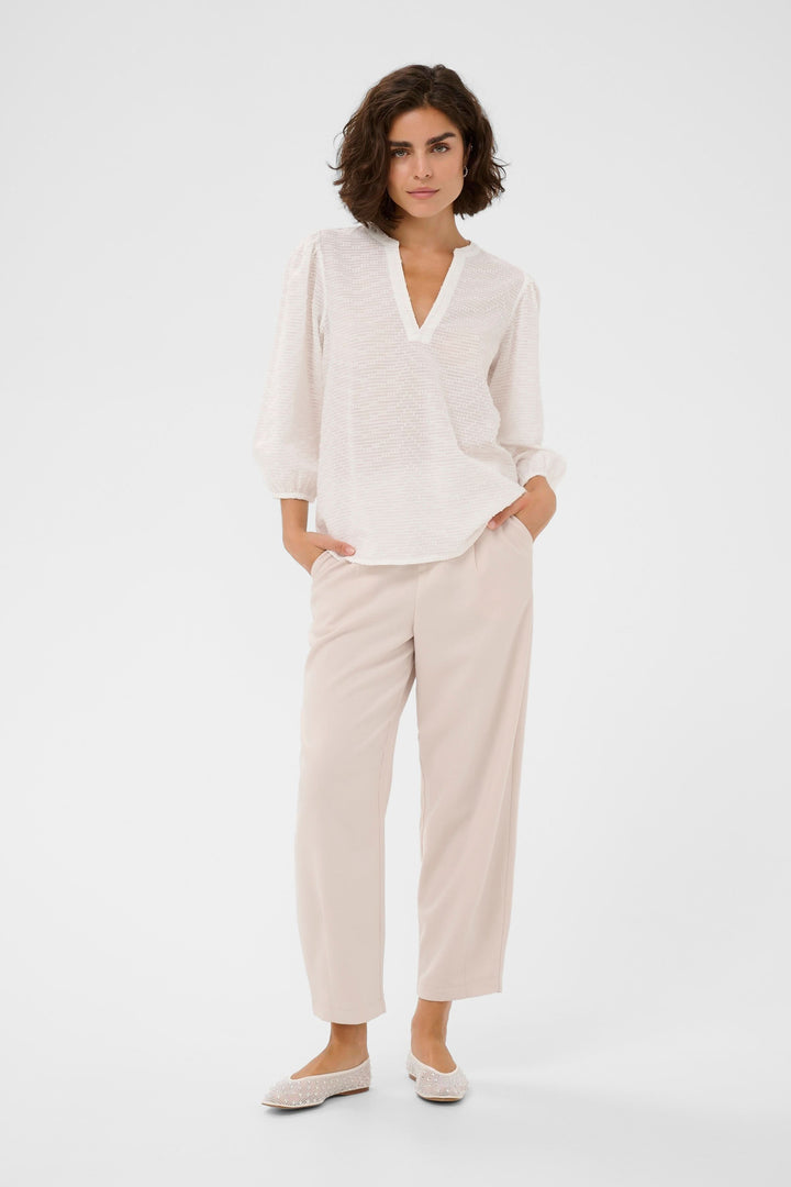 Femme portant la Blouse Penelope texturée à manches trois-quarts avec encolure en V et poignets élastiqués, design élégant et fluide.