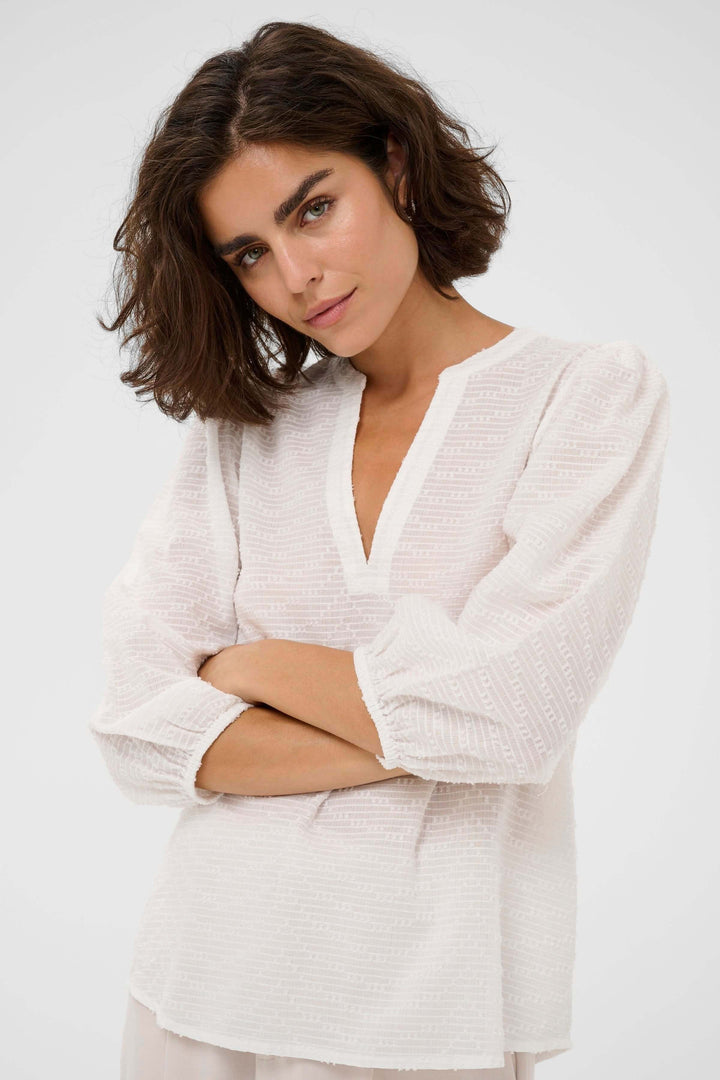 Blouse Penelope texturée à manches trois-quarts en tissu léger avec encolure en V, tenue féminine et moderne.