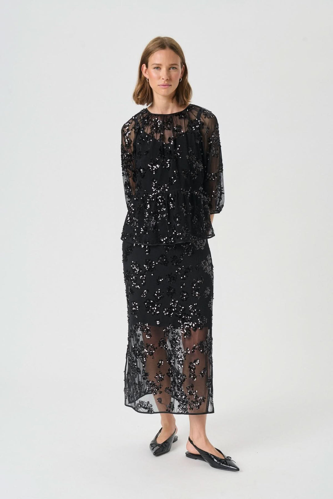 Modèle portant une Blouse Vivan à sequins floraux avec jupe assortie, montrant une allure élégante et sophistiquée.