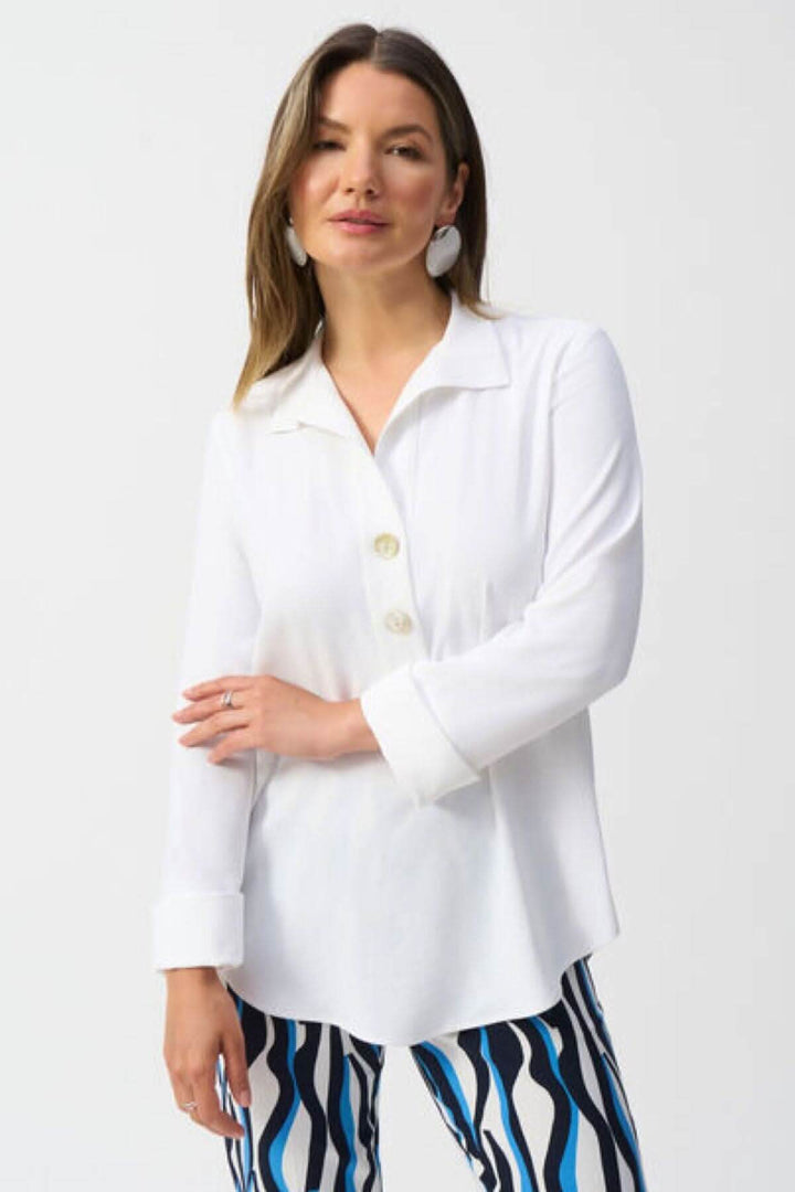 Blouse classique blanche avec col V, boutons, manches longues, style élégant et coupe arrondie.