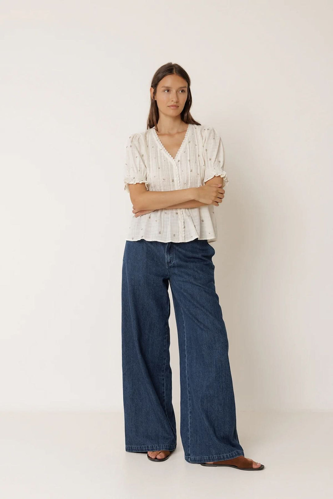 Blouse à encolure dentelle avec manches courtes bouffantes, conçu en tissu léger et imprimé discret, portée avec un jean large.