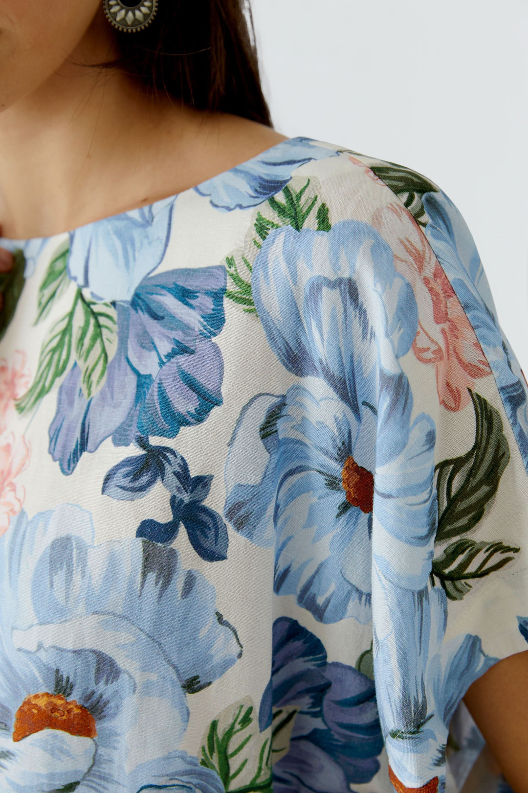 Blouse fluide à manches courtes avec motif floral bleu et rose, encolure arrondie, tissu léger reflétant élégance et confort.