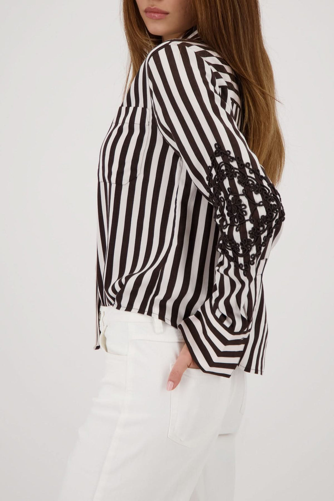 Blouse rayée avec broderies aux manches, motif rayé vertical noir et blanc, tenue élégante et confortable.
