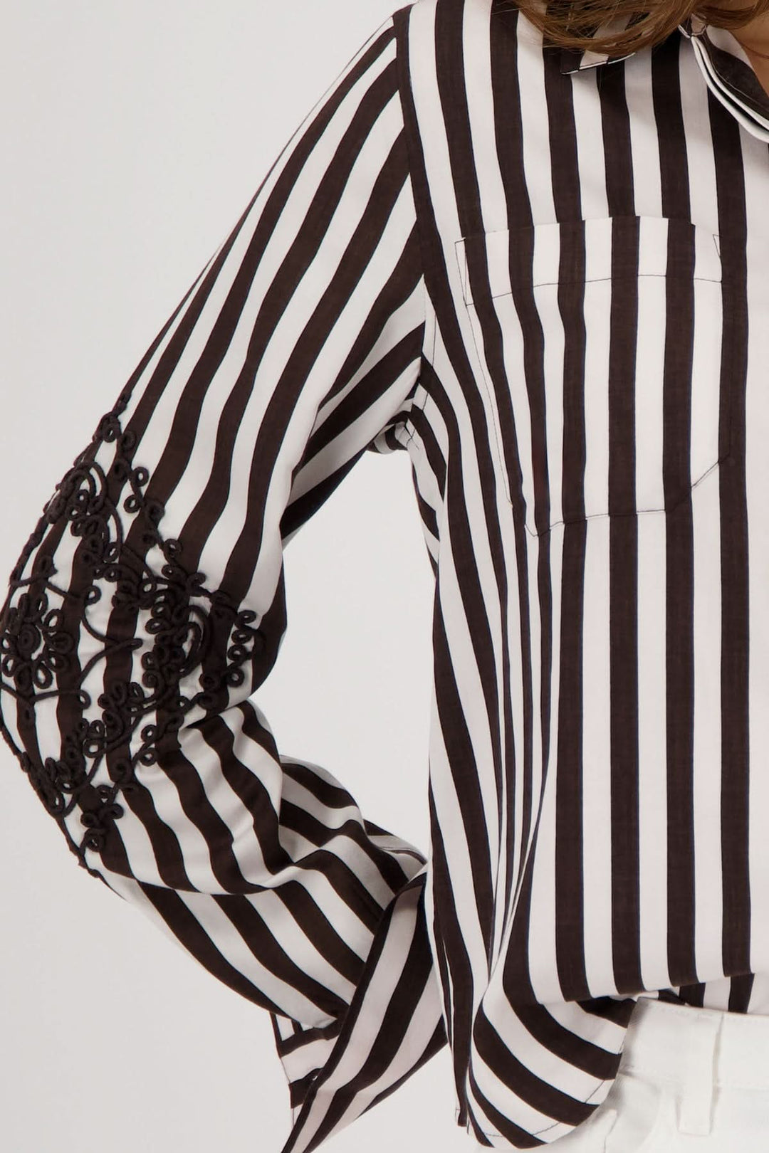 Blouse rayée avec broderies aux manches, motif graphique, contrastes élégants et coupe fluide pour confort au bureau et décontracté.