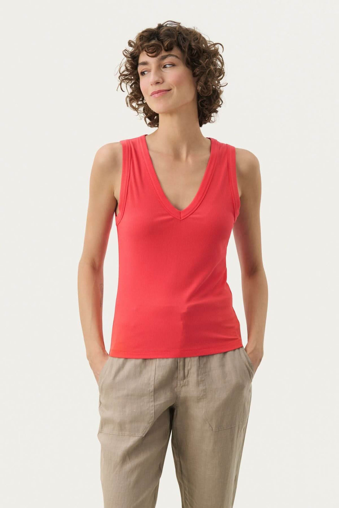 Camisole Nikkia en viscose douce, col en V, rouge, portée avec un pantalon beige, élégante et décontractée.