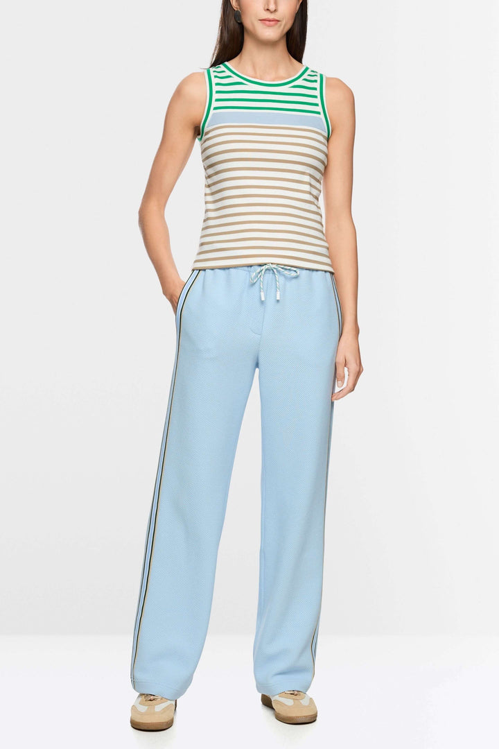 Femme portant une camisole rayé en coton avec encolure ronde contrastante, associée à un pantalon bleu ciel pour un look décontracté.