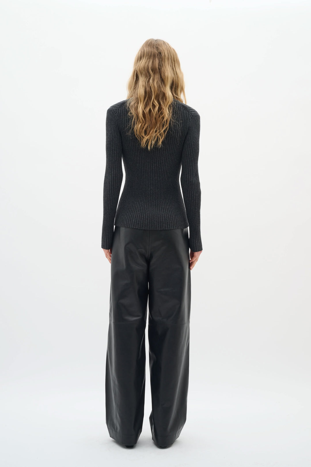 Vue arrière du Cardigan Gia en maille côtelée noire, porté avec un pantalon ample, touche élégante et féminine.