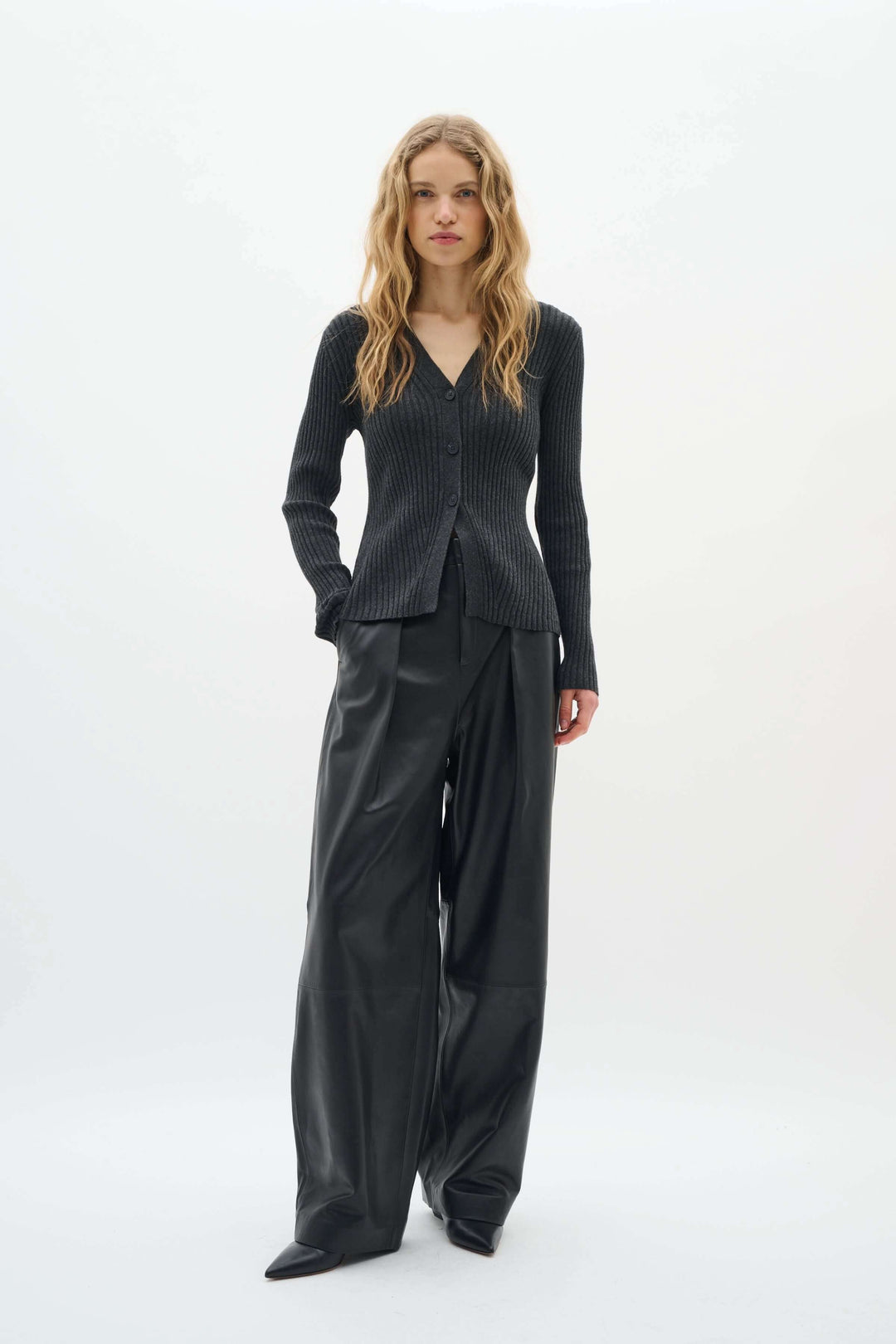 Cardigan Gia à côtes fines avec encolure en V, porté par un mannequin, look chic et confortable avec pantalon ample.