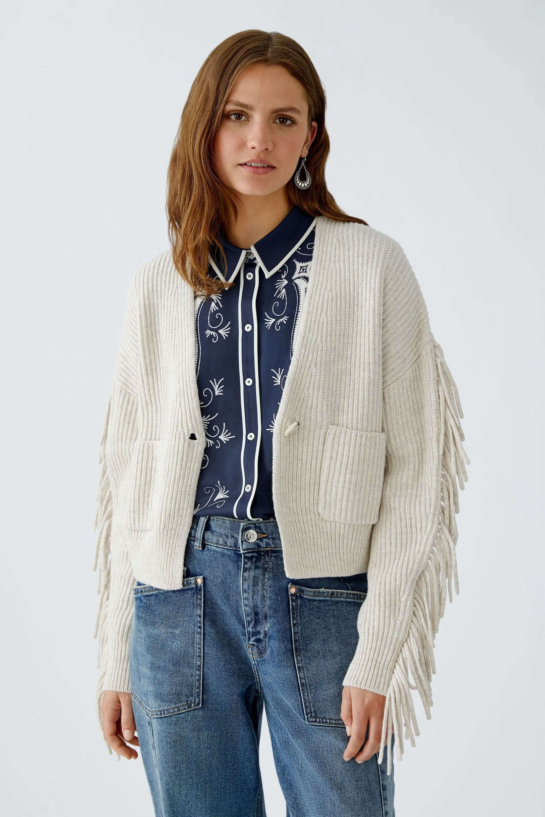 Femme portant un Cardigan avec franges en laine et coton, manches amples, poches plaquées, et fermeture à un bouton.