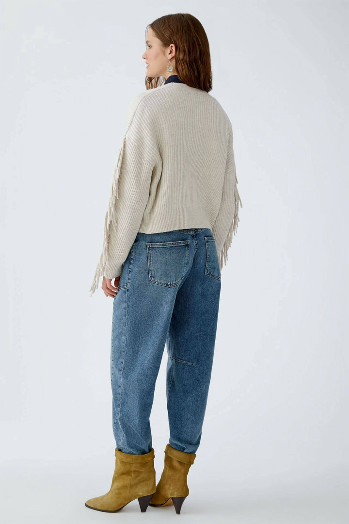 Femme portant un cardigan avec franges, coupe ample et longue, en laine et coton, offrant chaleur et douceur.