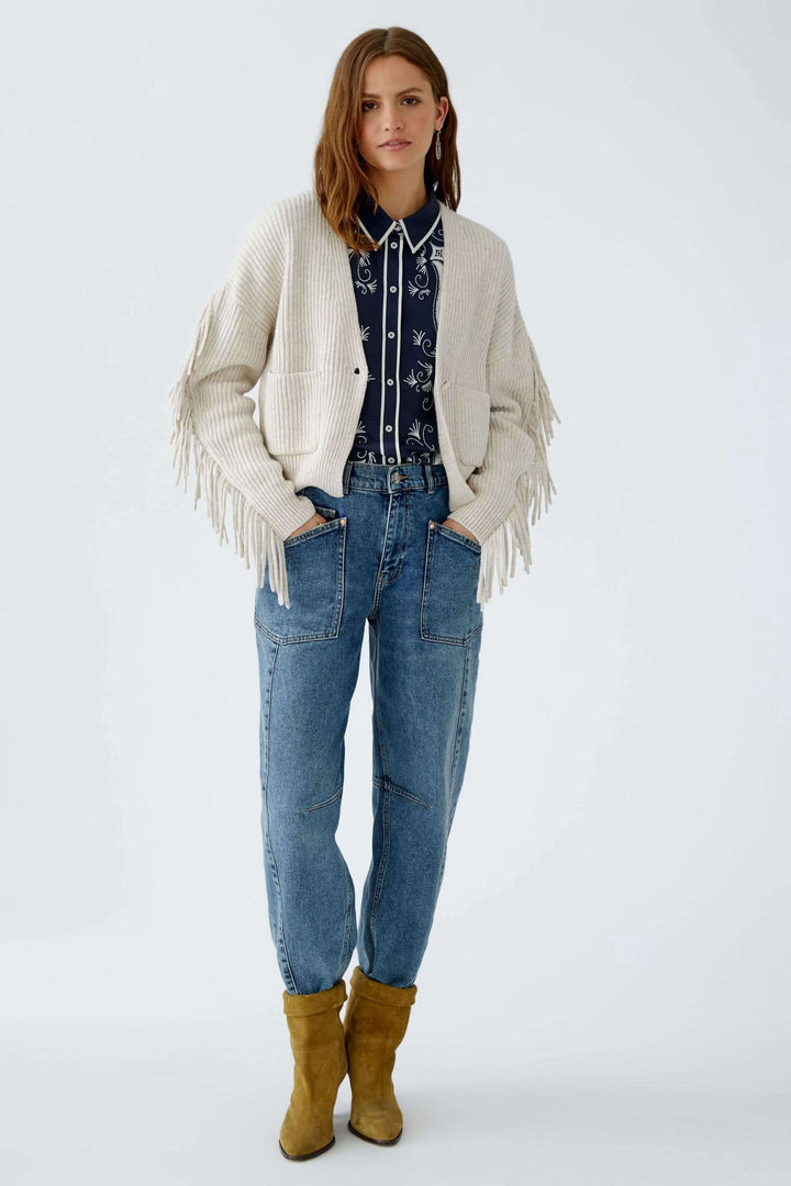 Femme portant un cardigan avec franges, coupe ample, décolleté en V profond avec fermeture à un bouton, tricoté coton laine.