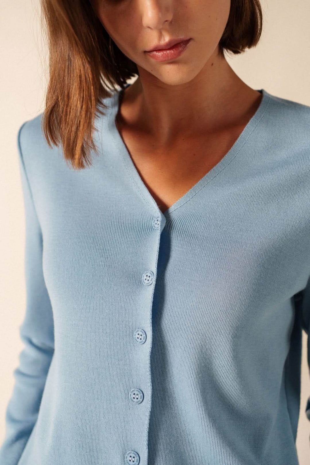 Cardigan de laine BREVANDS élégant avec encolure en V et boutons discrets, en maille douce bleue, porté par une femme.