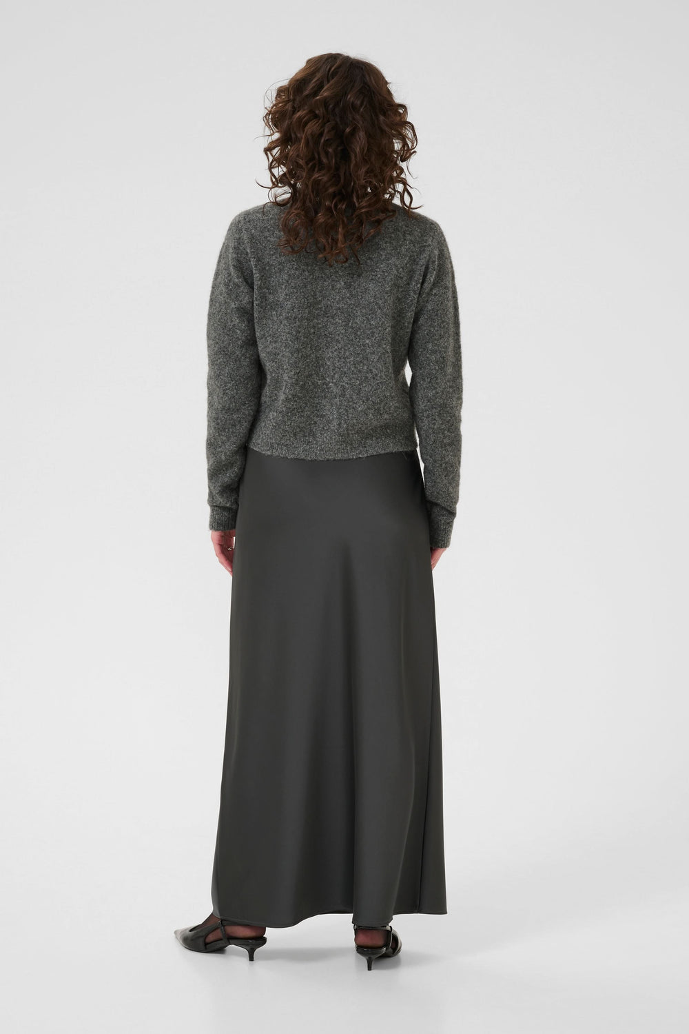 Dos d'un Cardigan en laine bouclée à col orné porté avec une jupe longue noire.