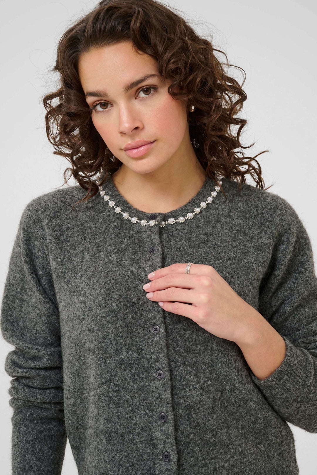 Cardigan en laine bouclée à col orné, femme portant un cardigan gris avec col décoré de perles, élégante et féminine.