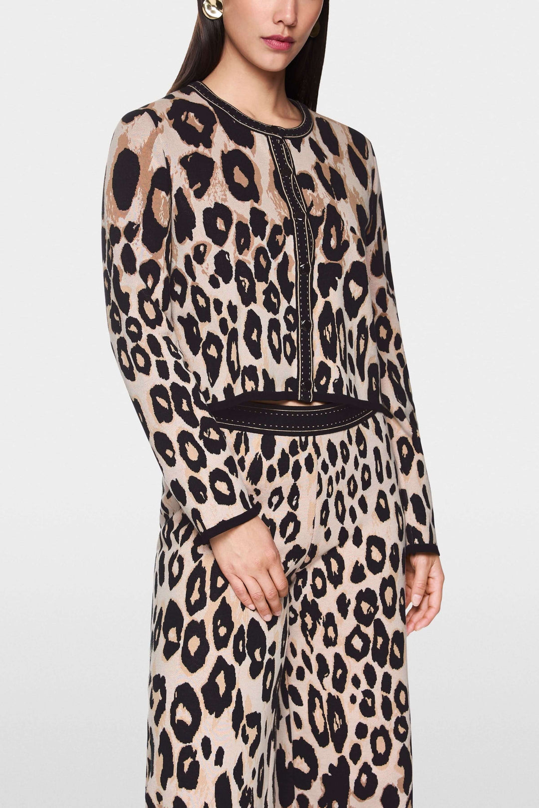 Femme portant un cardigan léopard à motif animal, coupe droite et finitions contrastées, une tenue audacieuse et moderne.