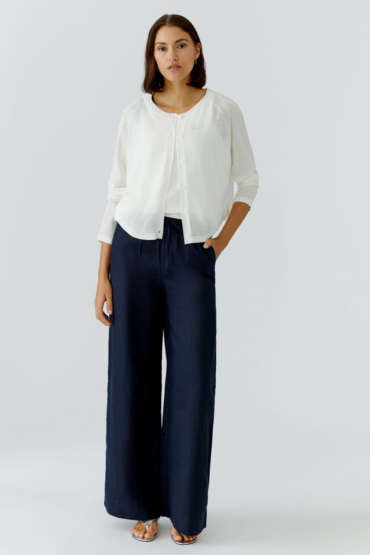 Femme portant un cardigan texturé boutonné avec pantalon large, look élégant et décontracté.