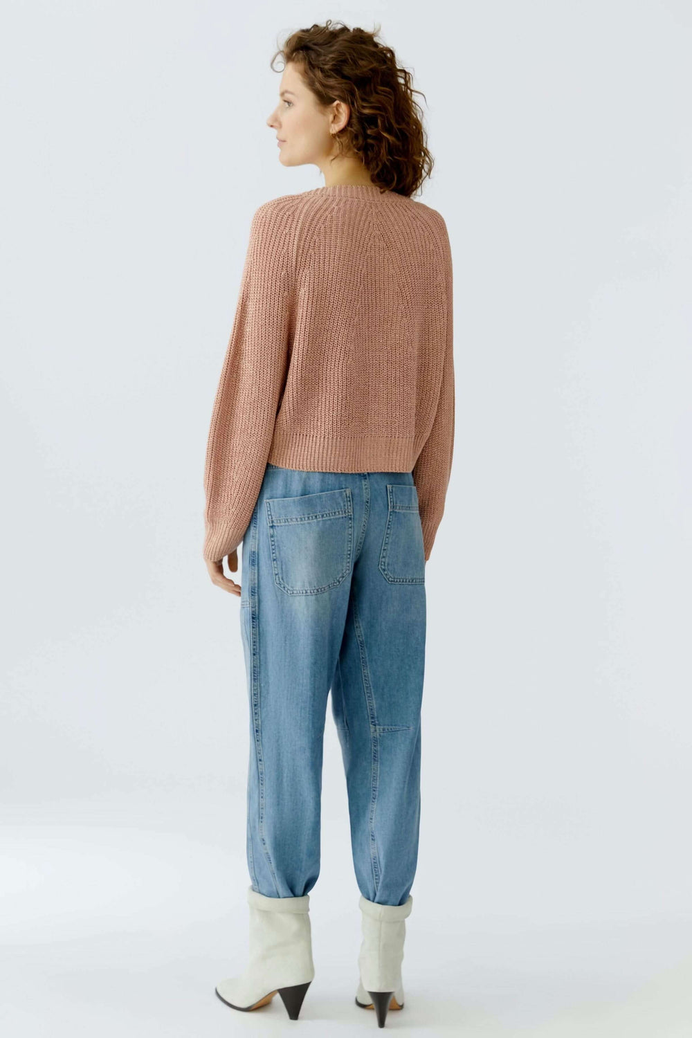 Cardigan tricoté en maille rose simple et élégant, coupe courte, femme de dos, style décontracté, essentiel du quotidien.