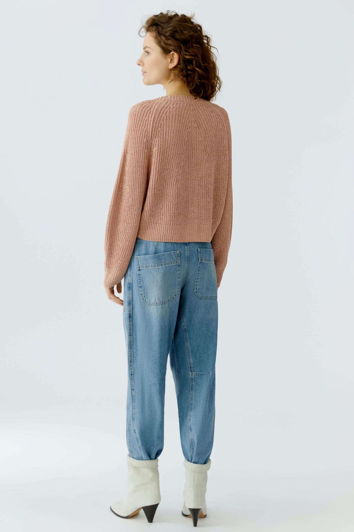 Cardigan tricoté en maille rose simple et élégant, coupe courte, femme de dos, style décontracté, essentiel du quotidien.