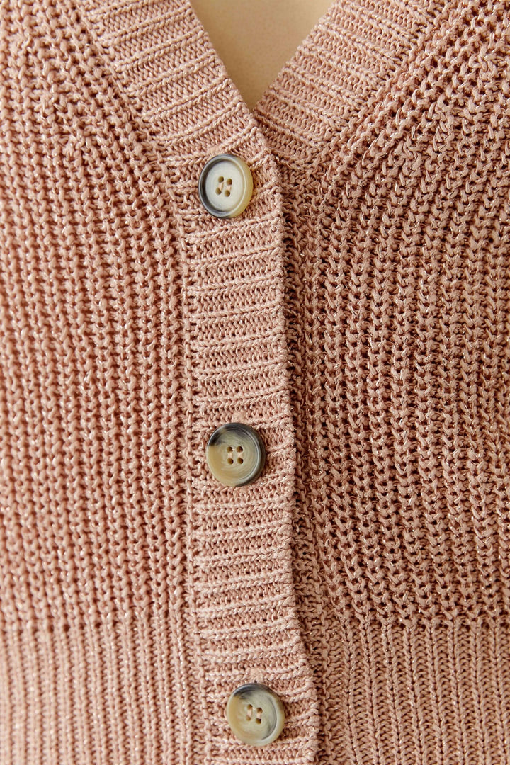 Gros plan sur le cardigan tricoté avec boutons classiques et encolure en V élégante pour une silhouette raffinée.
