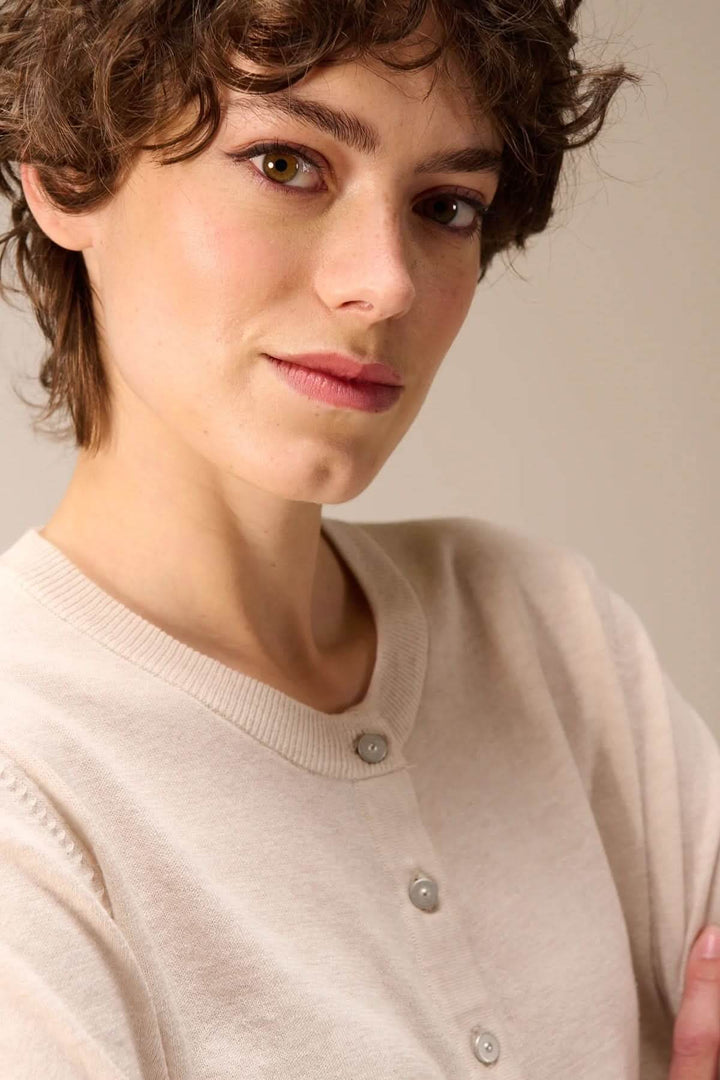 Femme portant un cardigan tricot fin boutonné col rond, détails élégants et confortables.