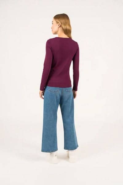 Femme vue de dos portant un chandail à manches longues violets et un jean large, élégant et décontracté.