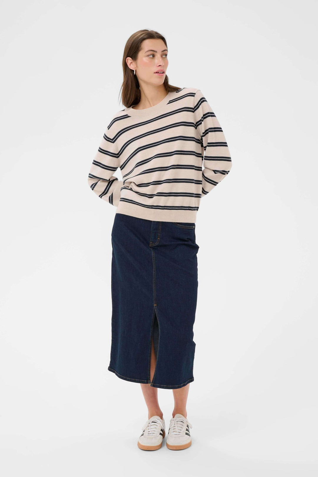 Chandail Yona à rayures avec coupe droite et col rond, porté avec une jupe en jean fendue et des baskets blanches.
