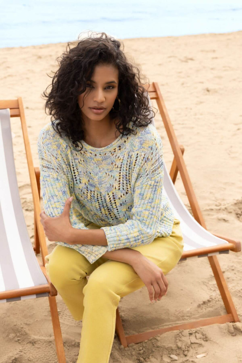 Femme portant un chandail ajouré à motif texturé sur la plage, en vacances d'été