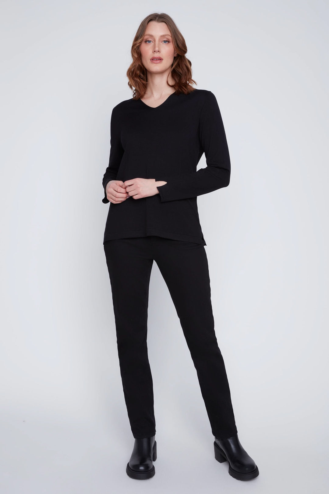 Femme portant un Chandail col V noir à manches longues avec un pantalon ajusté, illustrant un look chic et minimaliste.