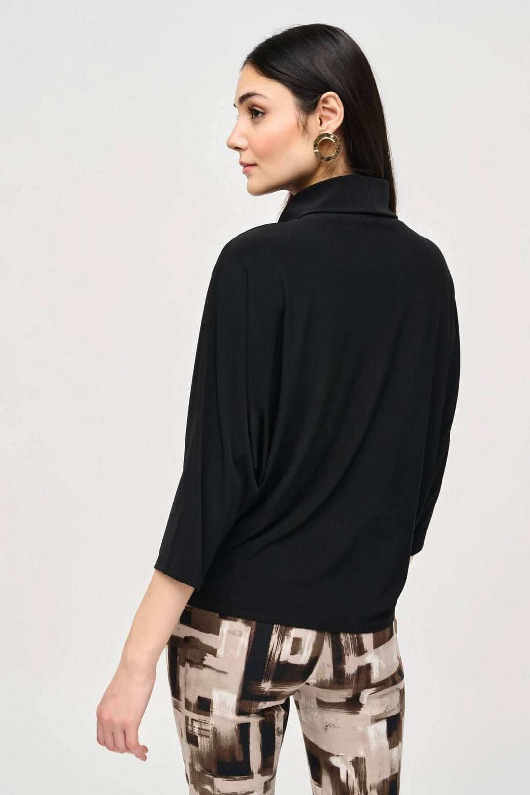Femme portant un chandail col bénitier noir avec manches 3/4, vu de dos, sur un fond neutre.