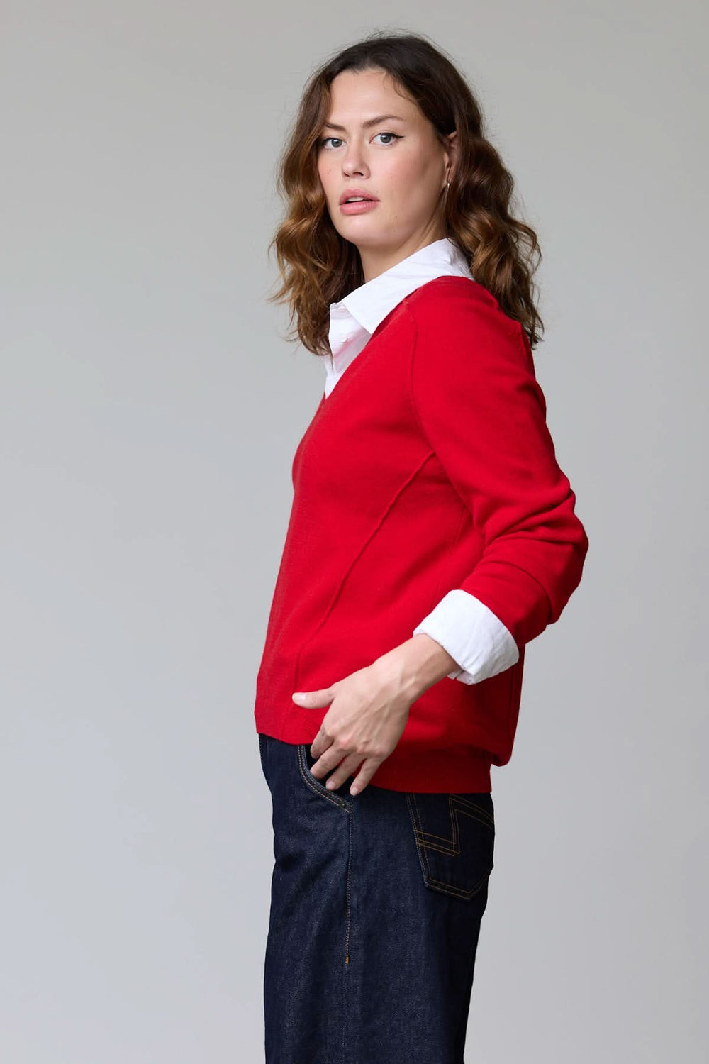 Femme portant un chandail col en V classique rouge avec chemise blanche en dessous, style élégant et polyvalent.