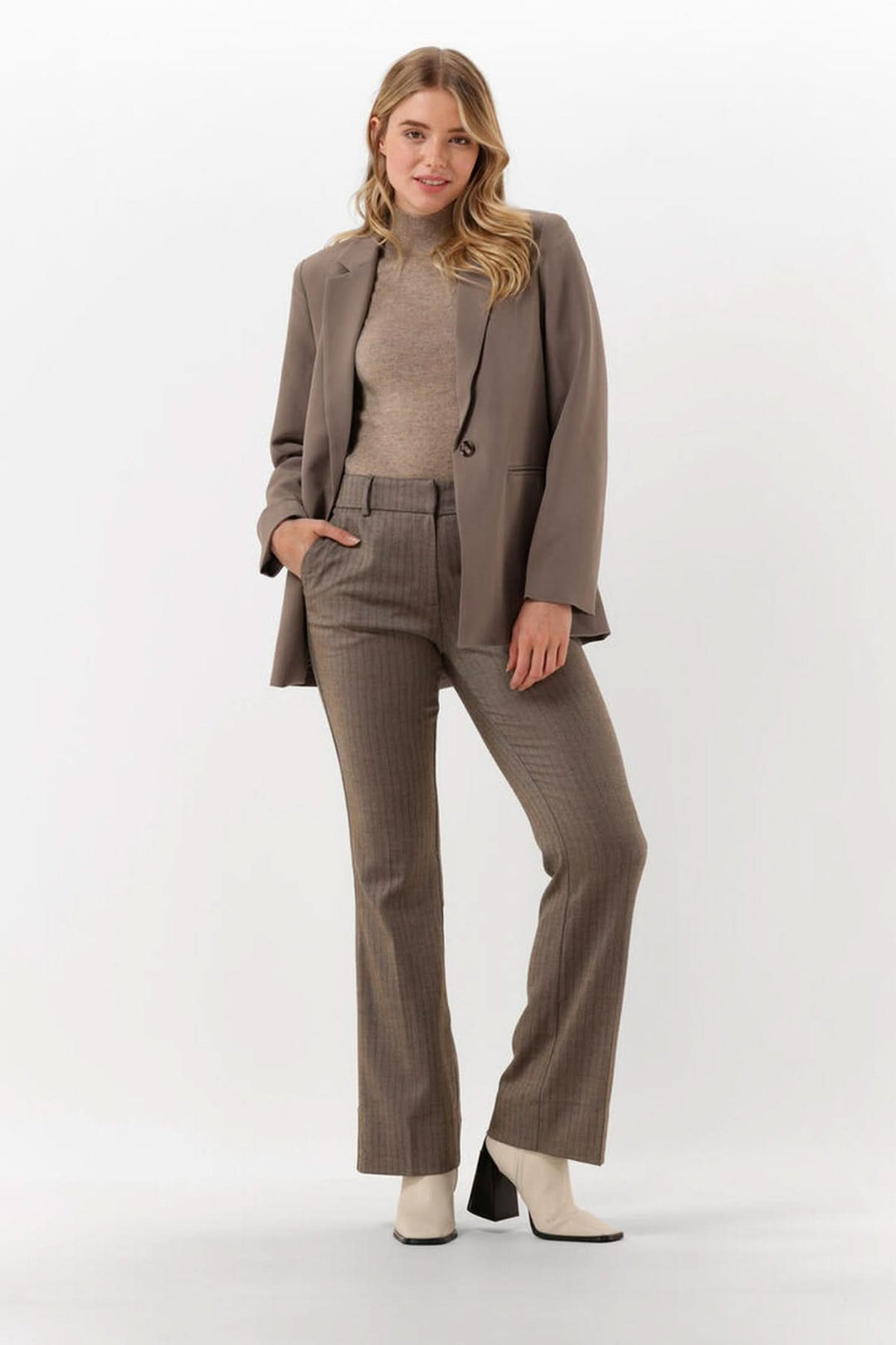 Femme portant un Chandail col montant manches courtes — maille fine sous un blazer, style élégant et moderne.