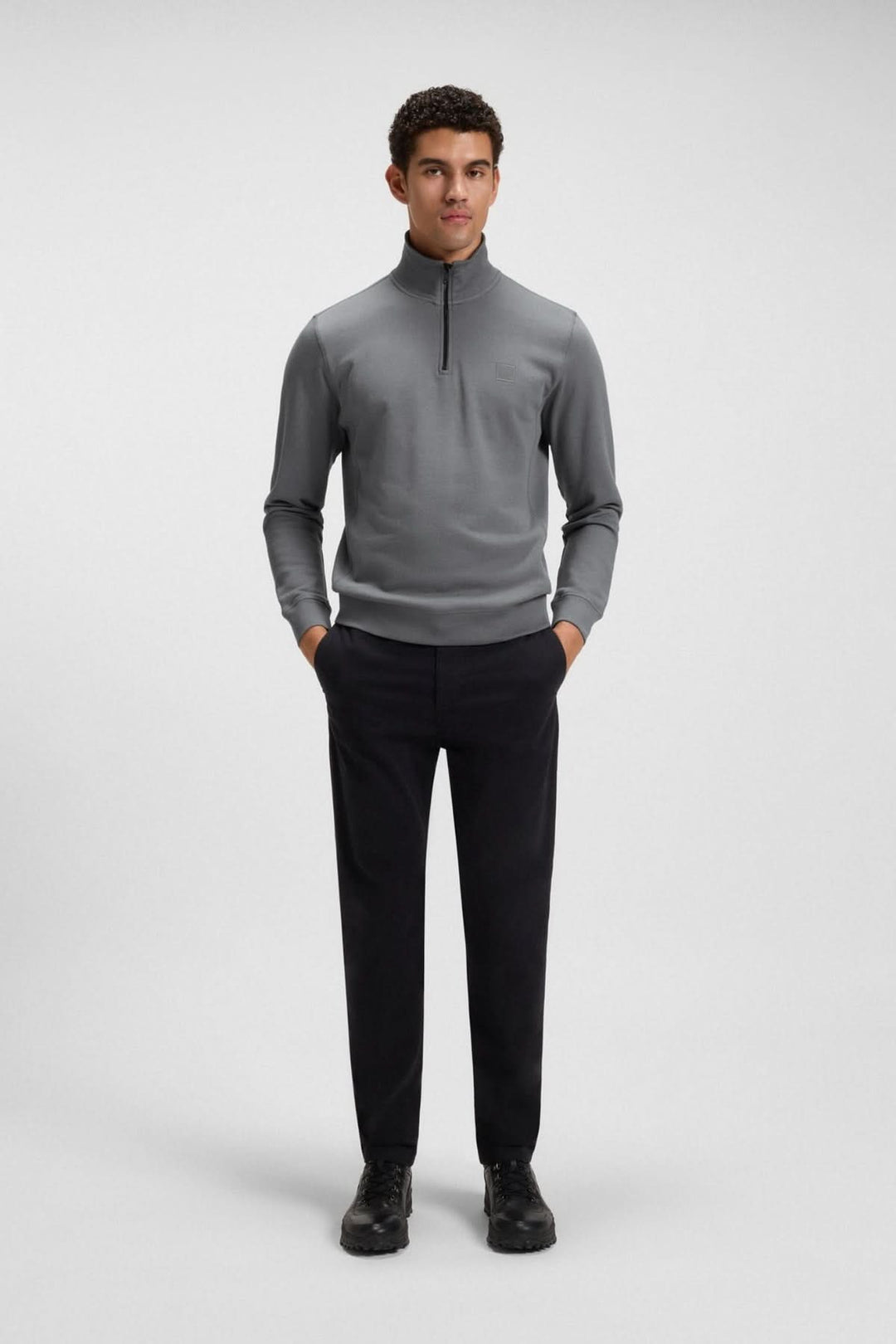 Homme portant un chandail à col montant zippé en coton Terry gris, manches longues, coupe régulière, sur fond gris neutre.