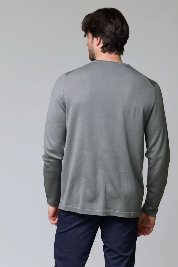 Homme portant un chandail col rond en tricot fin gris, vue de dos, montrant la maille douce et coupe ajustée. Décris moi le produit en français.