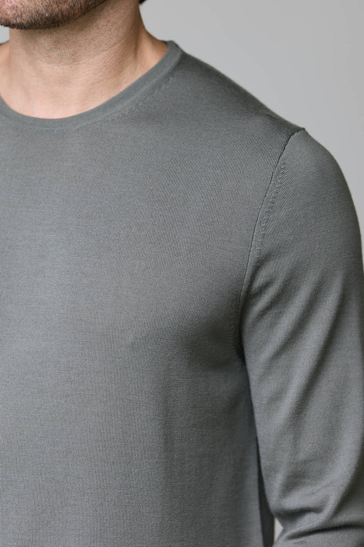 Homme portant un chandail col rond en tricot fin gris, coupe ajustée et texture douce, idéal pour un look élégant et confortable.