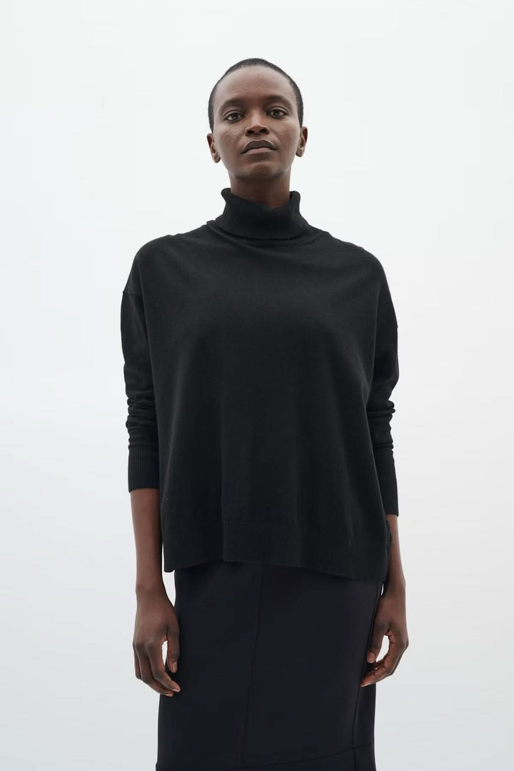 Femme portant un chandail à col roulé coupe décontractée Glea noir, manches longues, manches côtelées, chic et minimaliste.