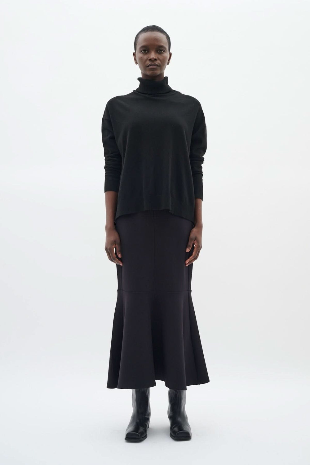 Chandail à col roulé coupe décontractée Glea noir avec manches longues et finitions côtelées, porté avec une jupe pour un look chic.