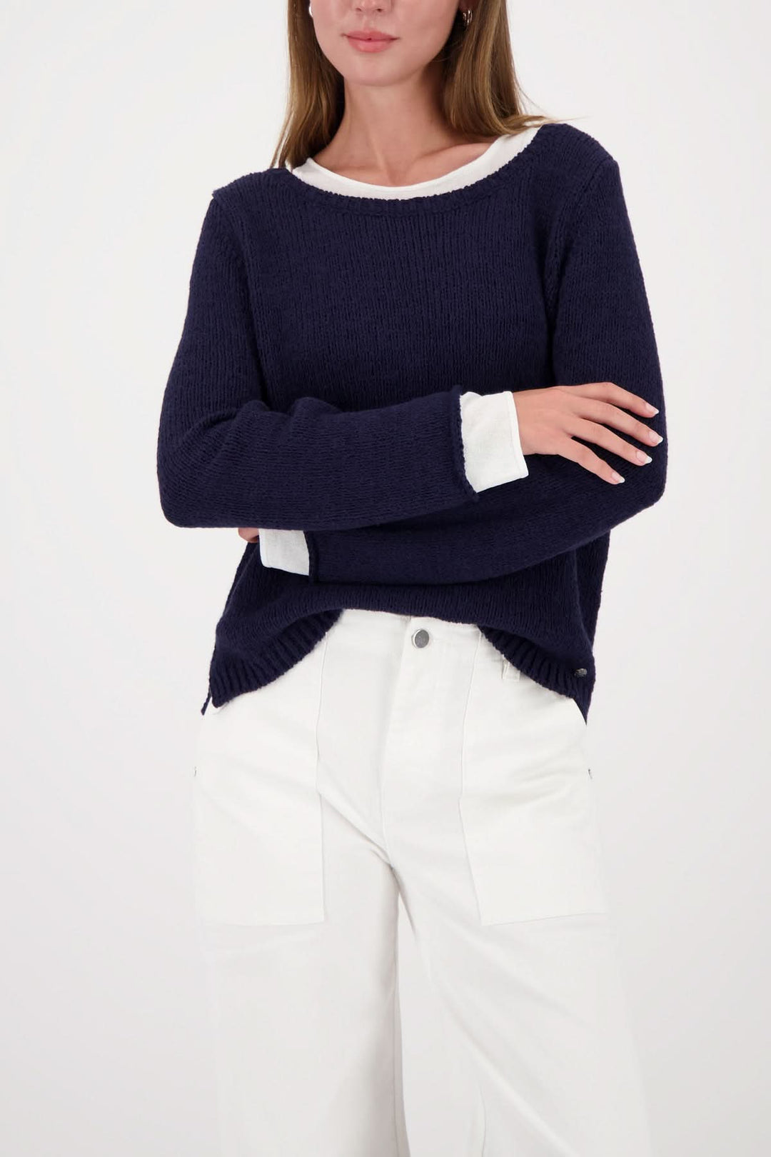 Femme portant un chandail à effet superposé col rond bleu avec finitions contrastantes, look moderne et épuré.
