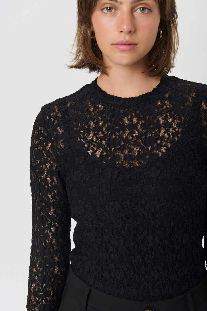 Chandail en dentelle Venetia noir élégant porté par une femme, manches longues, encolure ronde, tissu délicat.
