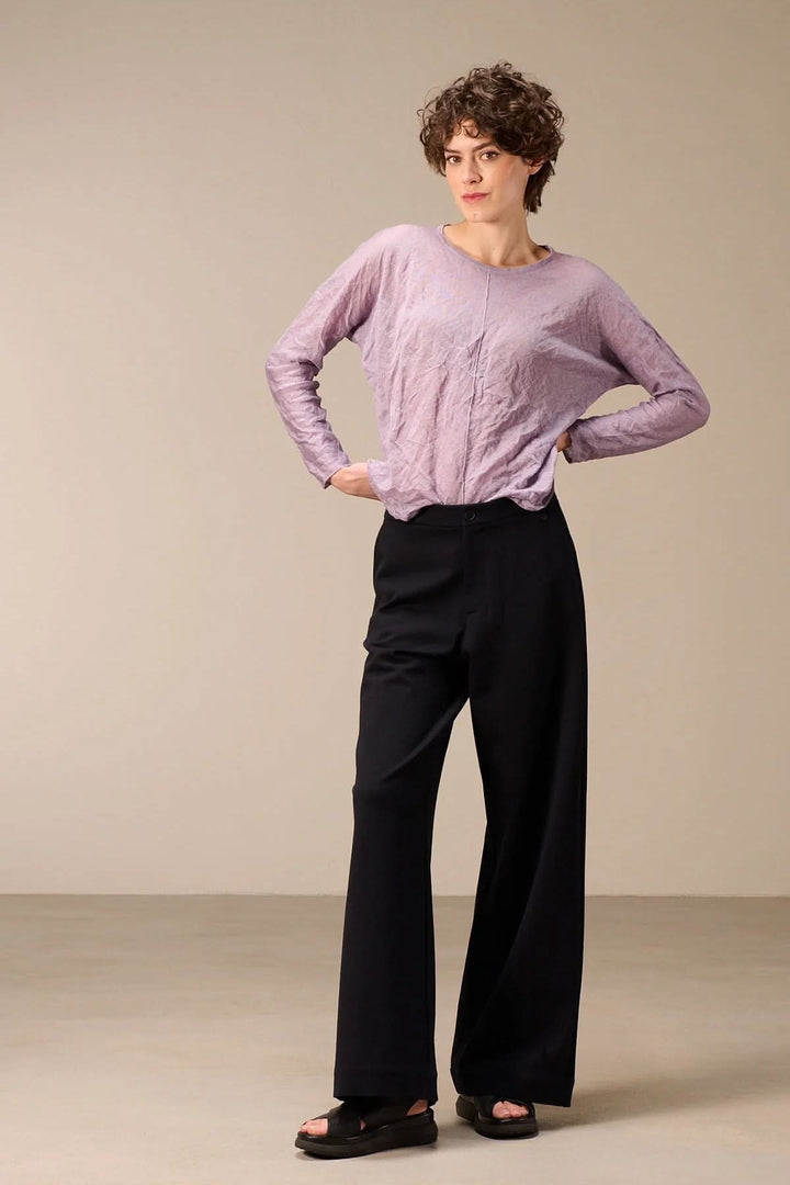 Femme portant un chandail en maille fine avec un design froissé et une encolure ronde, style décontracté et moderne.