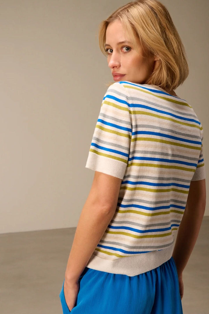 Chandail en maille rayé manches courtes porté par une femme de dos, motif rayé bleu et beige pour un look polyvalent.
