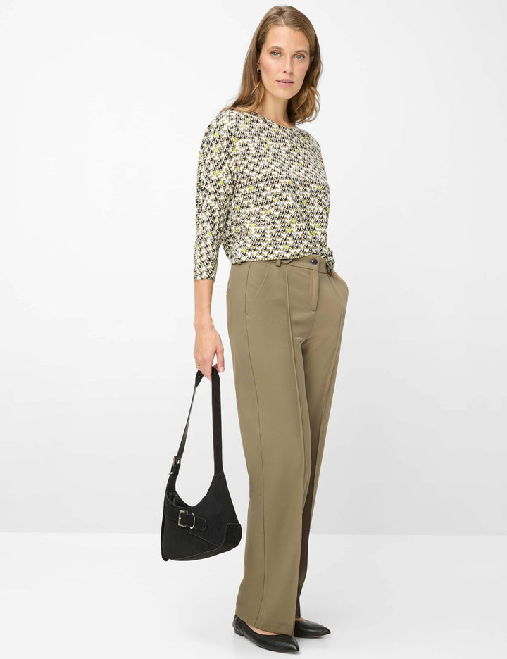 Femme portant un chandail imprimé graphique CHARLENE, manches trois-quarts, coupe droite, avec un pantalon beige et un sac noir.