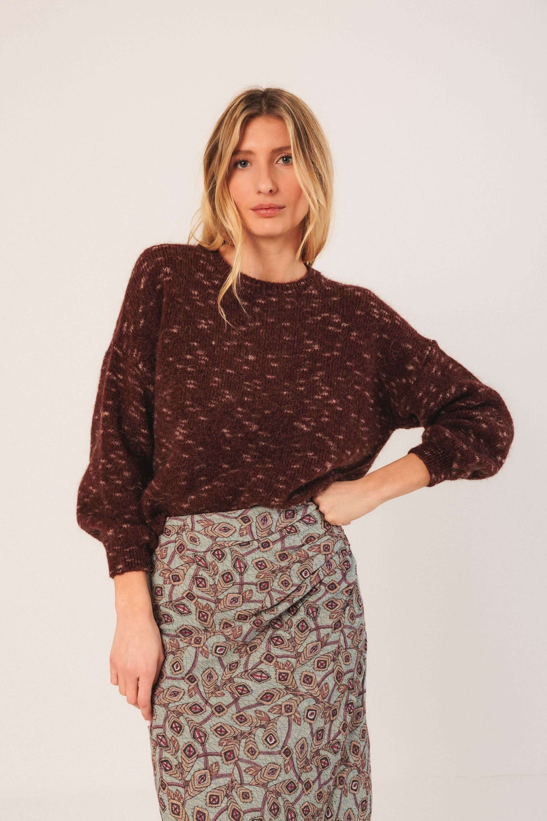 Femme portant un Chandail maille texturée marron avec jupe imprimée, style décontracté et tendance, idéal pour la saison froide.