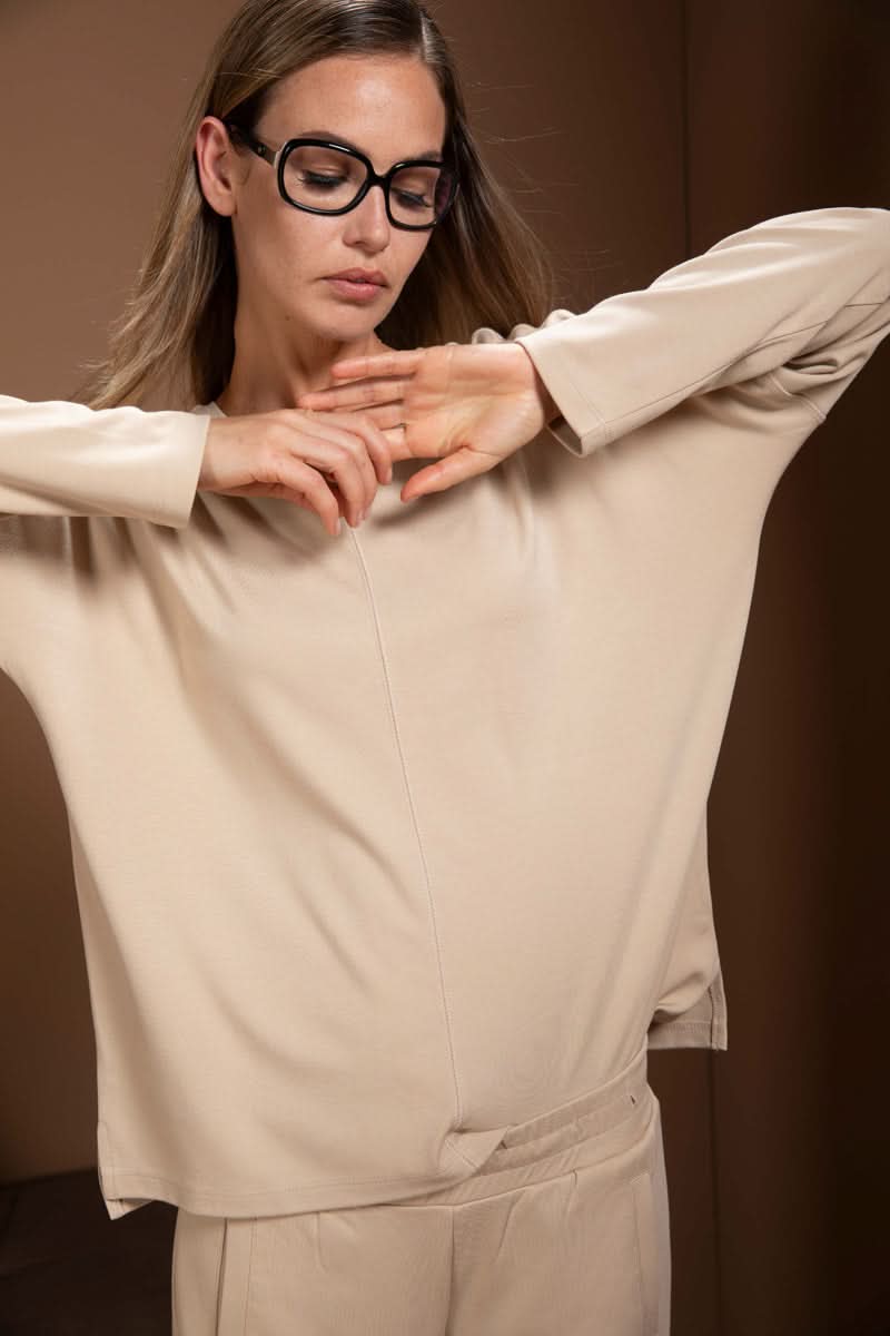 Chandail minimaliste beige à manches longues, encolure en V, style décontracté avec épaules tombantes, parfait pour look moderne.