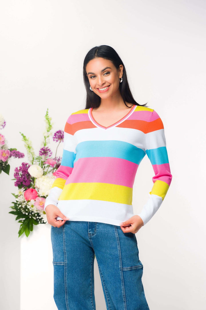 Chandail à rayures coloré en maille fine avec encolure en V porté par une femme souriante devant un bouquet de fleurs.