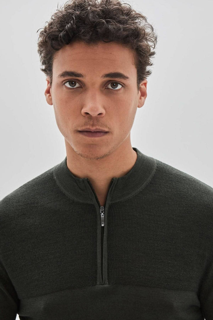 Homme portant un chandail zippé Newbury en laine mérinos, couleur verte, avec col montant et fermeture à glissière.
