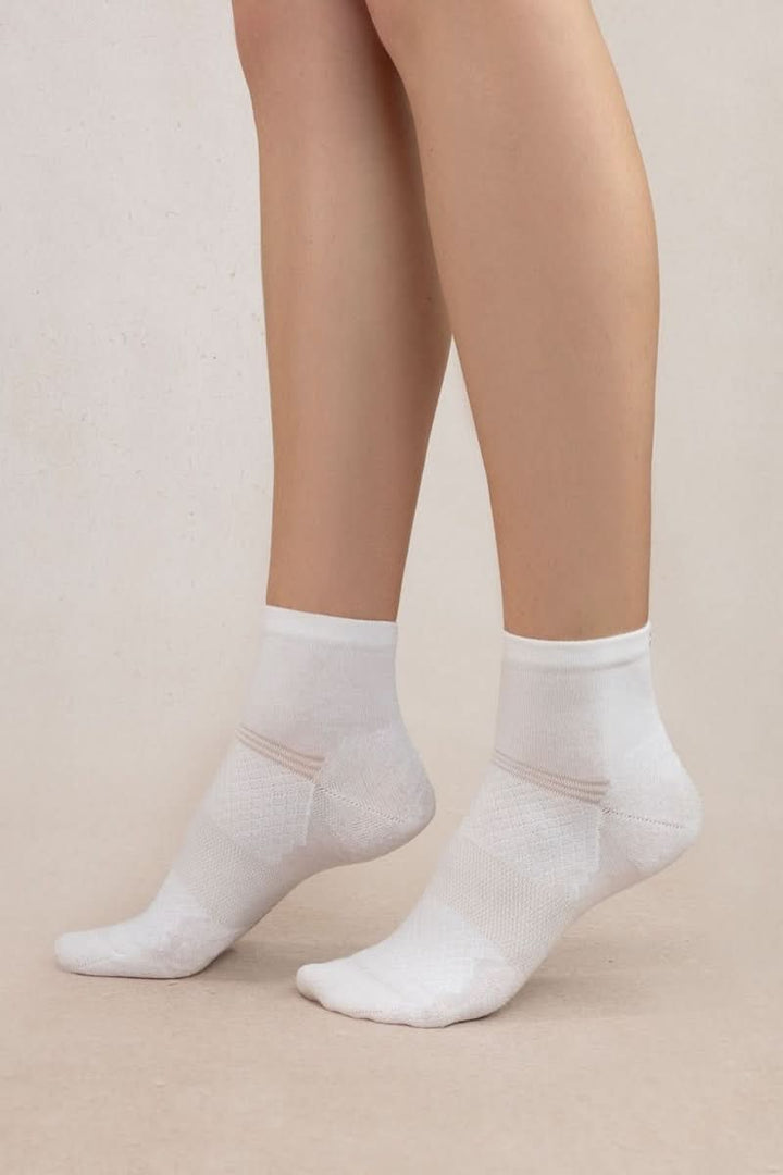 Person wearing chaussettes courtes en maille respirante blanches, confortables et techniques, idéales pour activités quotidiennes.